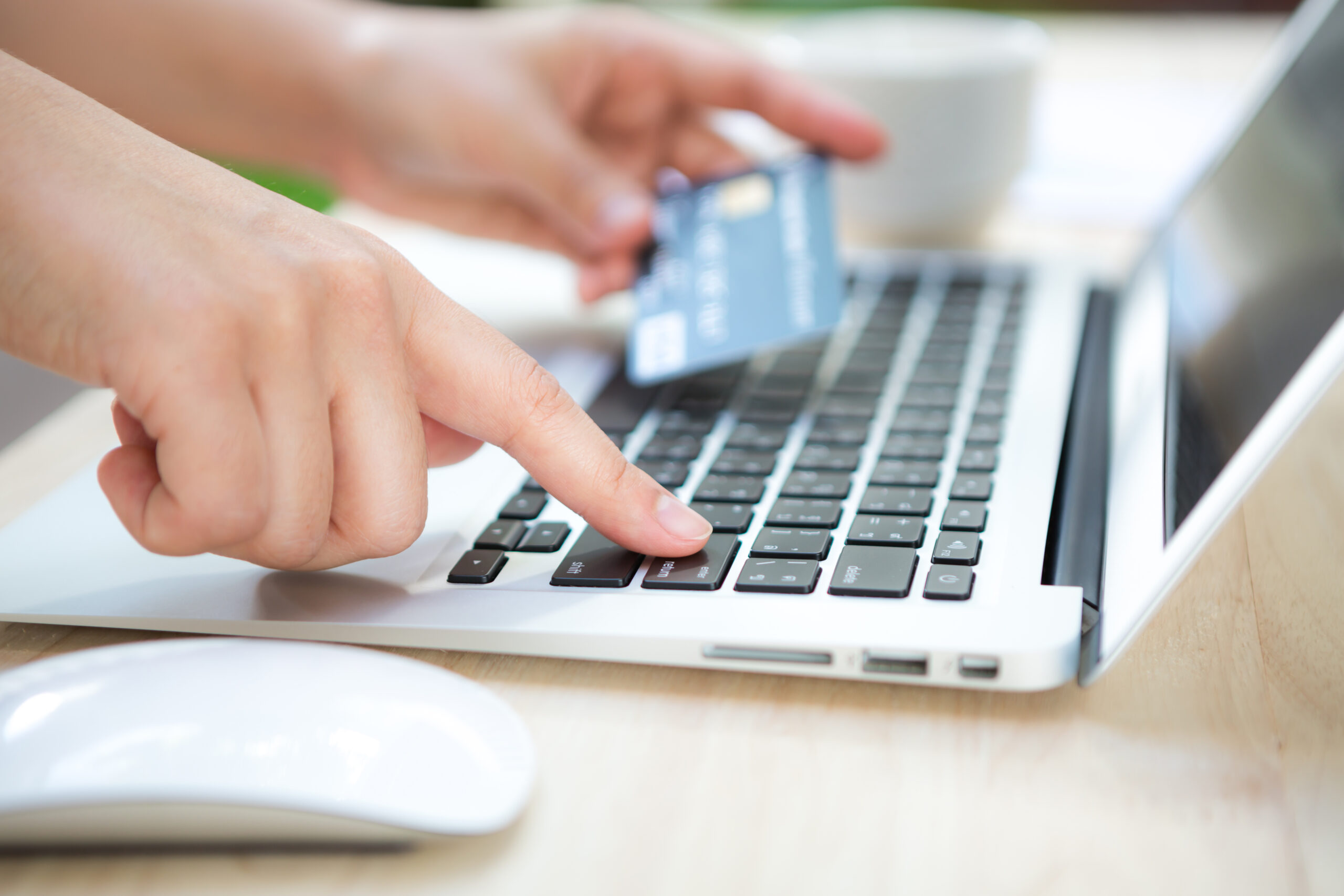Hands holding a credit card and using laptop computer for online ilustracna